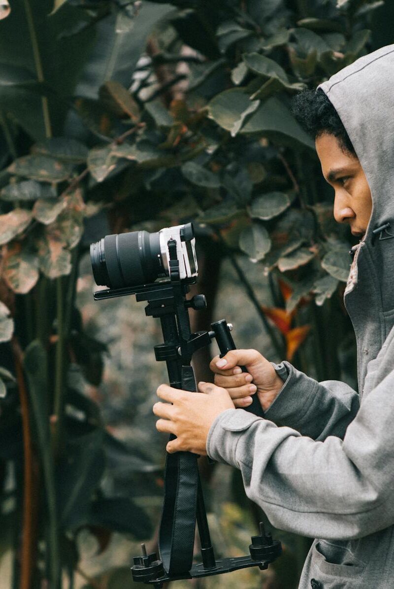 man in hooded jacket holding camera with stablizer