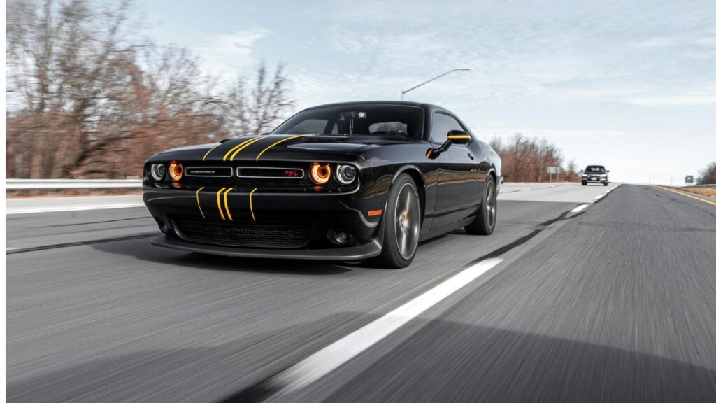 Black sports car with yellow racing stripes driving fast on a highway, representing alert and smart travel on the road.