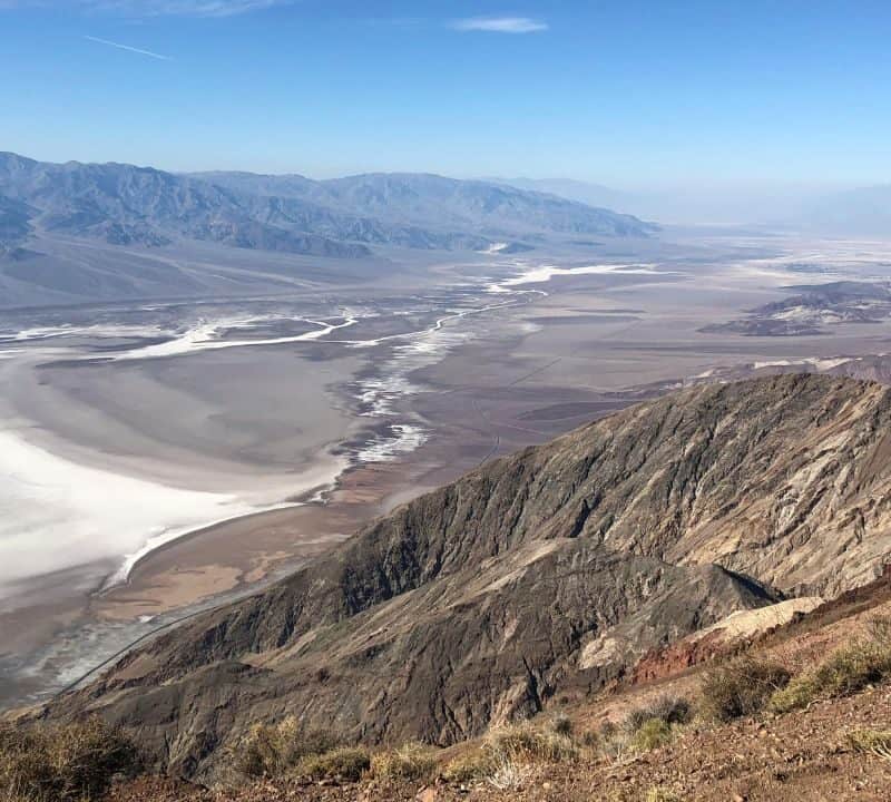 View from Dante’s View in Death Valley showing salt flats, desert floor, and rugged mountains under clear blue sky.