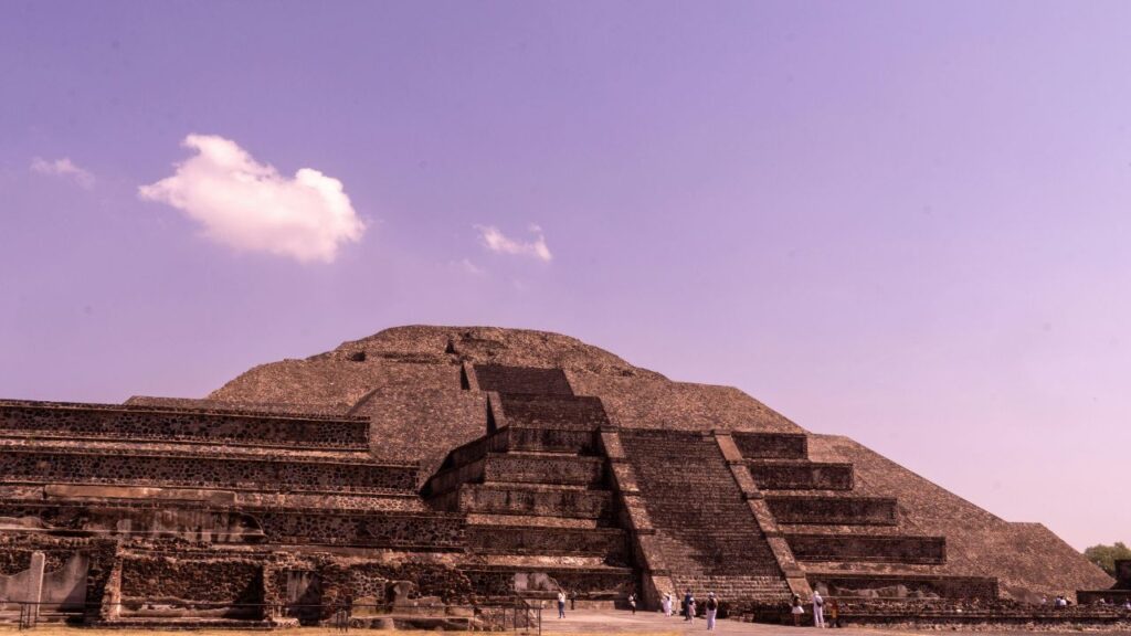 The Pyramid of the Sun at Teotihuacan in Mexico with its massive stone steps and terraced structure under a clear sky with a few clouds.