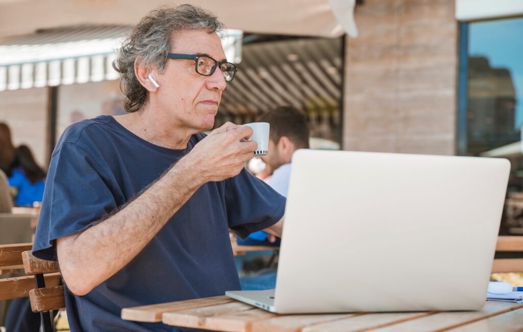 older person using laptop in cafe