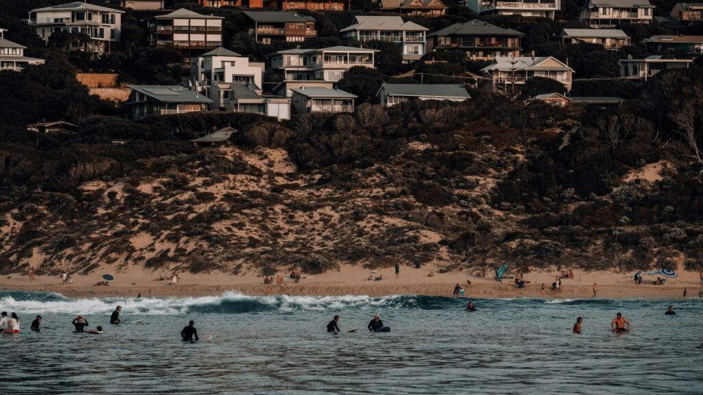 Surfers and beachgoers enjoying waves below hillside homes on California’s Central Coast.