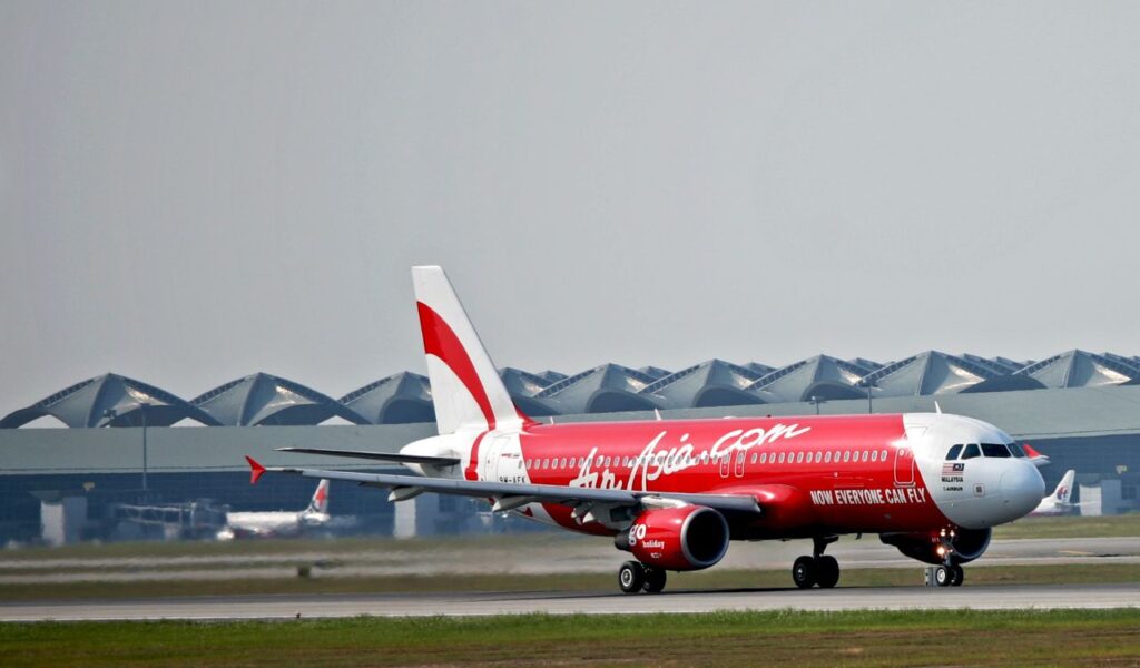 AirAsia aircraft on the tarmac, sporting its bold red livery and the slogan “Now Everyone Can Fly.
