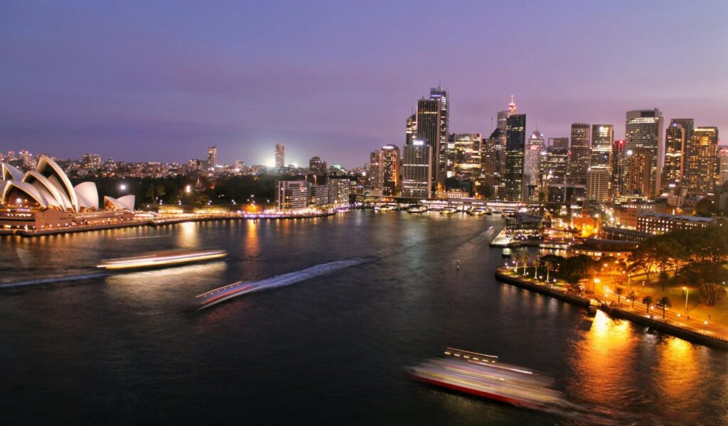 Sydney skyline at dusk with Opera House and boats on the harbor, Australia city view.