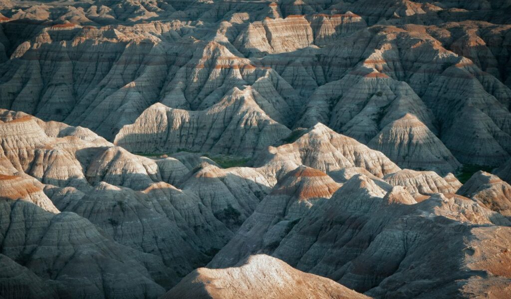 Eroded rock formations create a maze of jagged ridges and layered peaks, casting shadows across Badlands National Park.