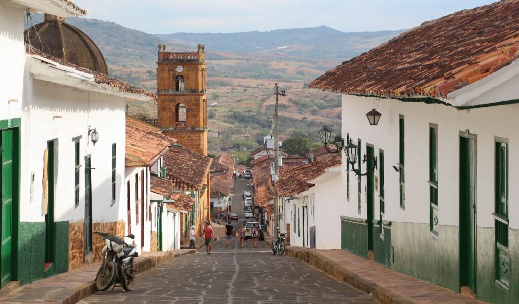 Cobblestone street and colonial buildings in Barichara, Colombia, with mountain views in the background.