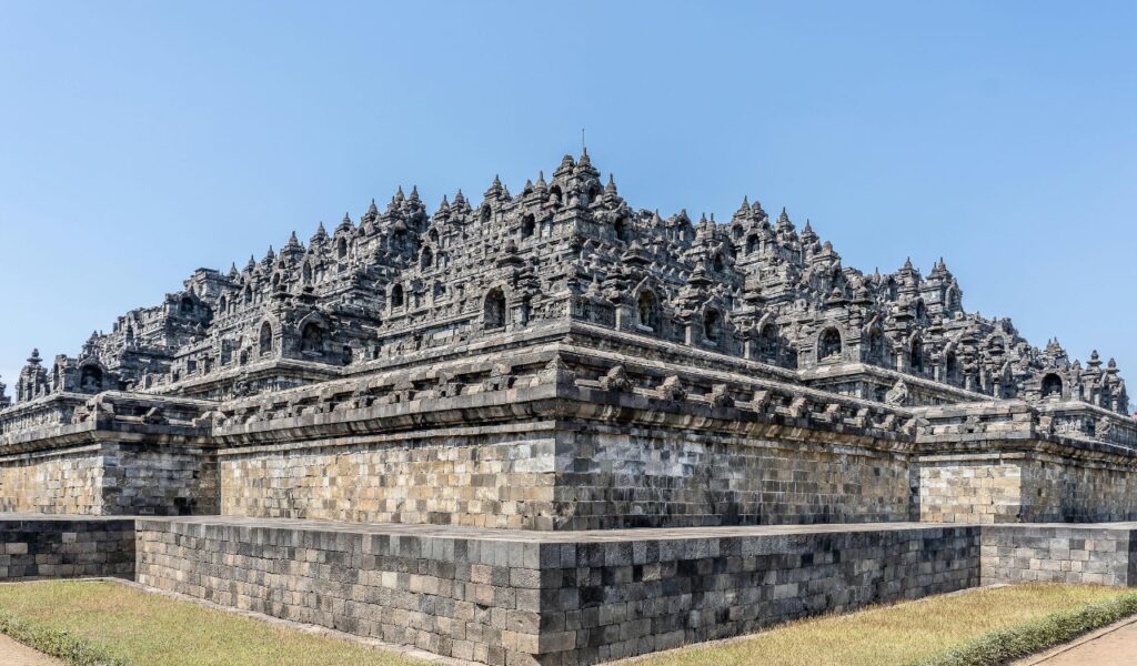 Borobudur Temple in Indonesia with its intricate stone carvings and tiered design, set against a clear blue sky.