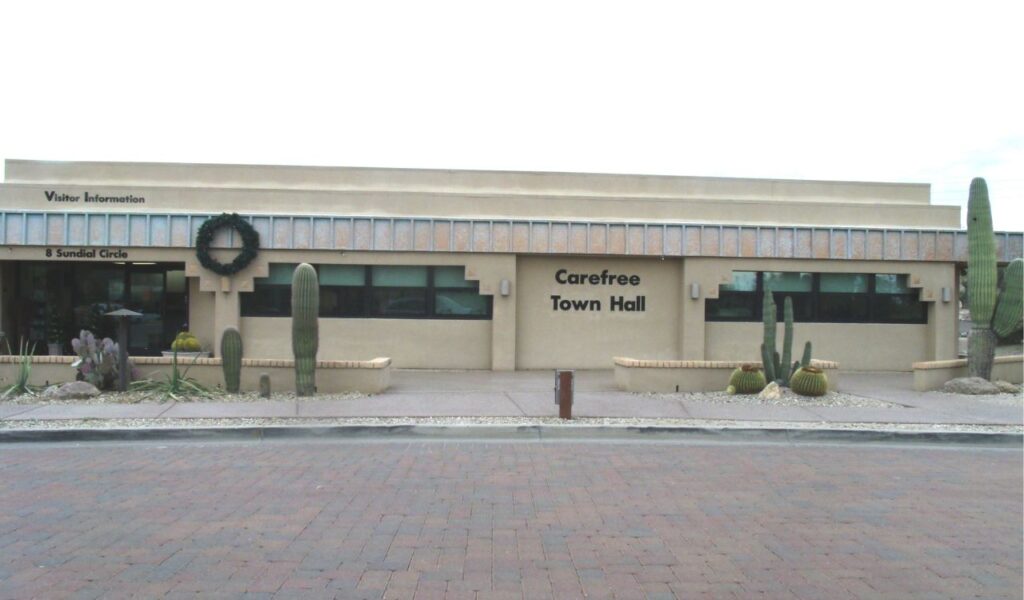 Front view of Carefree Town Hall building with desert plants.