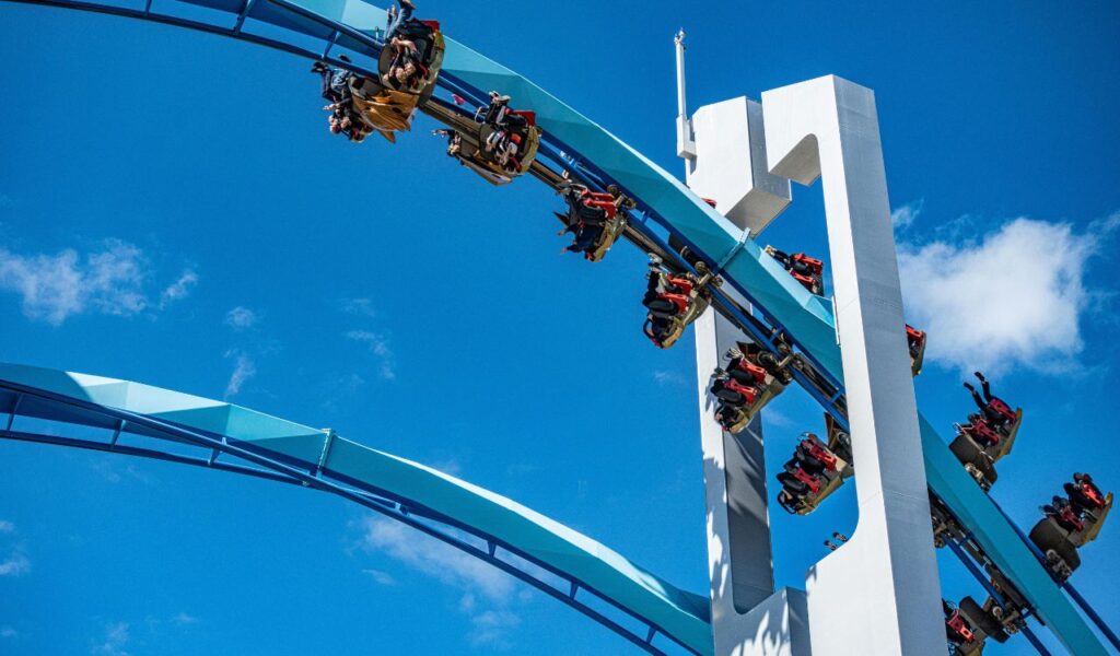 A thrilling roller coaster ride at Cedar Point in Ohio with riders soaring along a curved blue track against a clear blue sky.