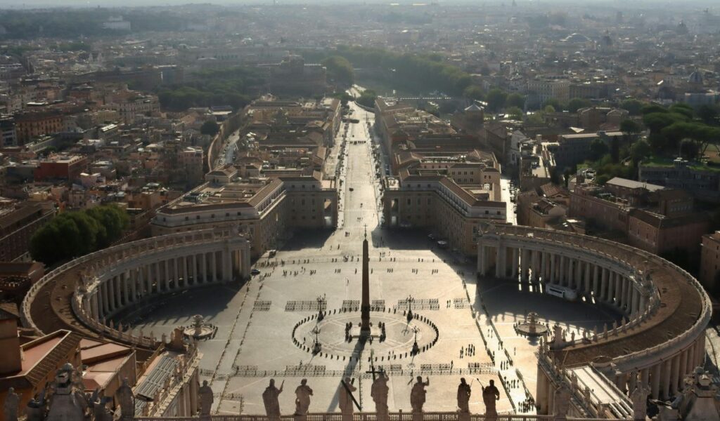 Aerial view from the top of St. Peter’s Basilica Dome overlooking St. Peter’s Square, the obelisk, colonnades, and cityscape of Rome.