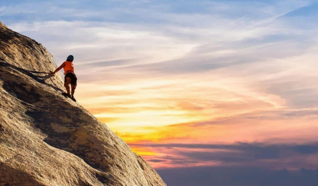 A climber ascending a steep rock face at sunset near Humbug Mountain on the Oregon coast