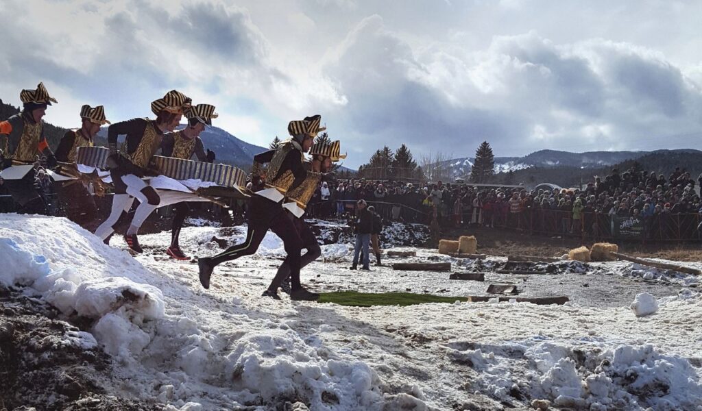 Costumed racers run through snow in a winter mountain event.