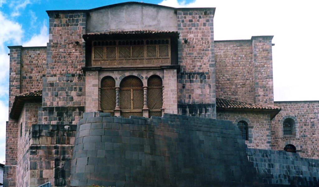 Stone walls of Coricancha in Cusco, Peru, with colonial architecture built atop the ruins of the Inca sun temple.