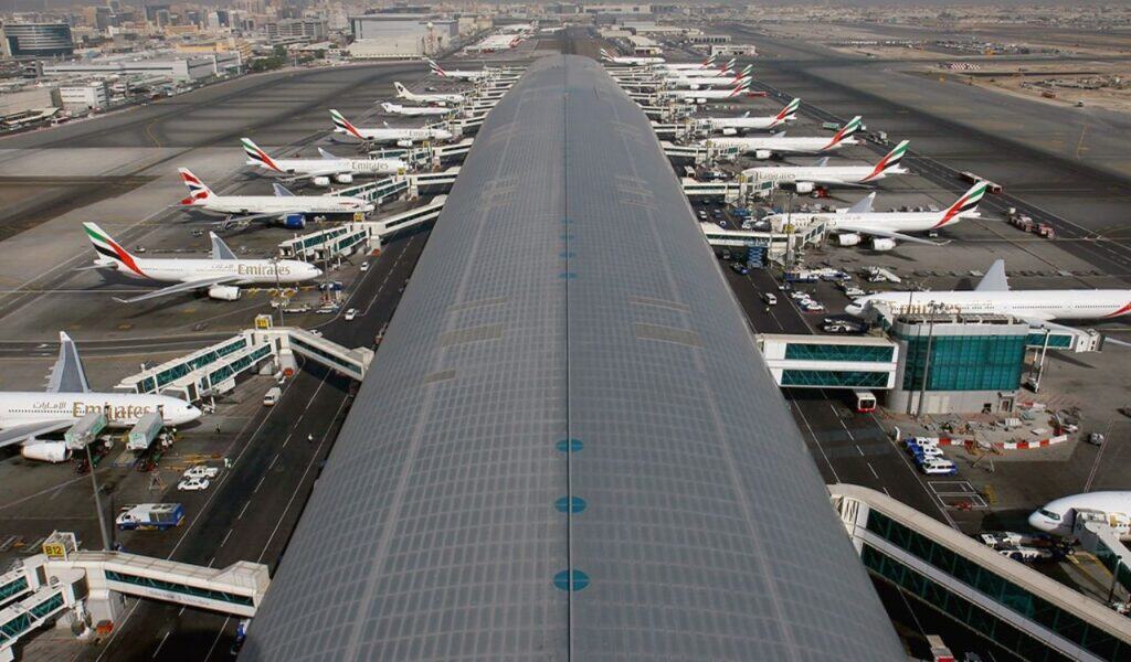 Aerial view of Dubai International Airport’s Terminal 3 with Emirates aircraft lined up at gates on both sides of the concourse.