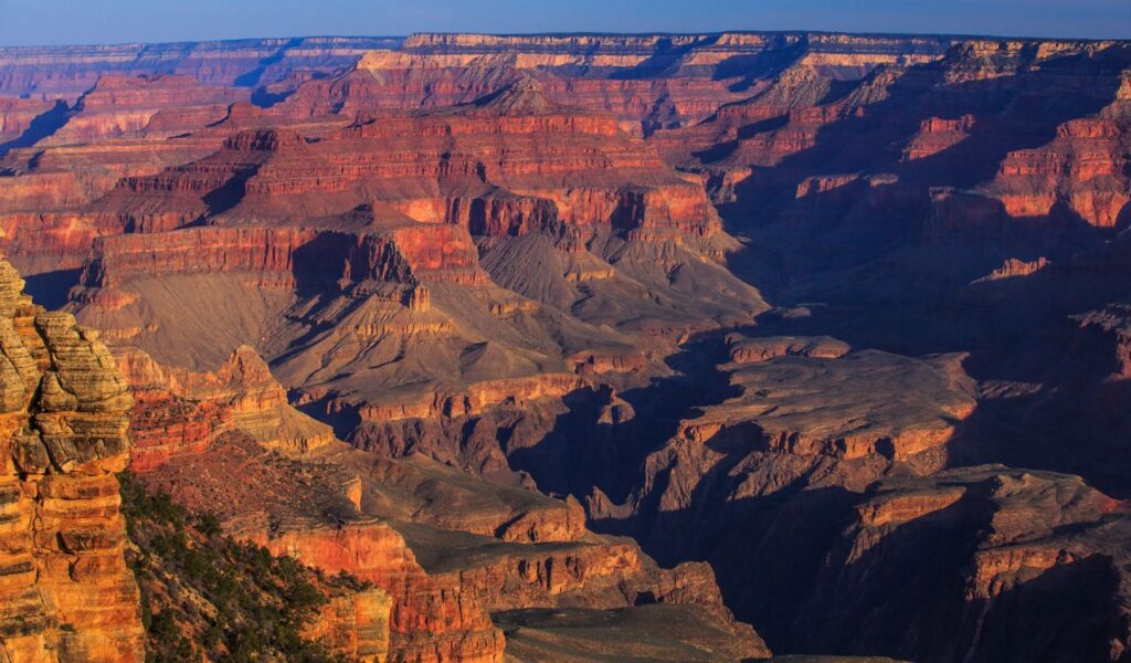 Sunlit view of Grand Canyon cliffs and deep valleys in Arizona.