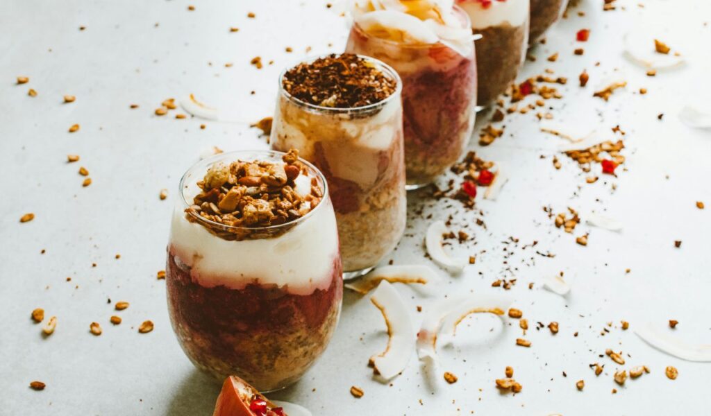 Row of layered yogurt parfaits topped with granola.