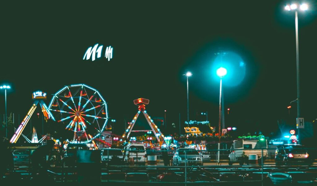 Night view of Hanayashiki Amusement Park in Tokyo, Japan, featuring a Ferris wheel, brightly lit rides, and colorful lights against the dark sky.