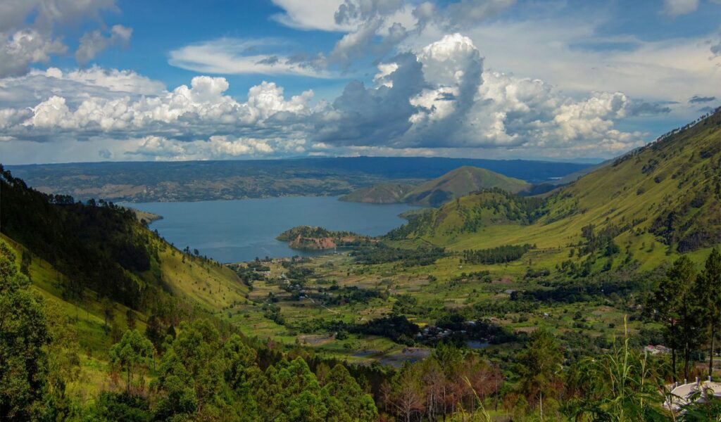 Lake surrounded by green hills and cloudy sky in Sumatra, Indonesia.