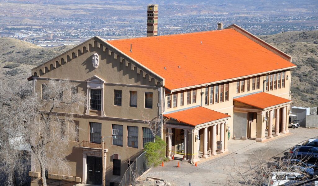 Historic Jerome Grand Hotel with orange roof overlooking Arizona hills and desert valley below.