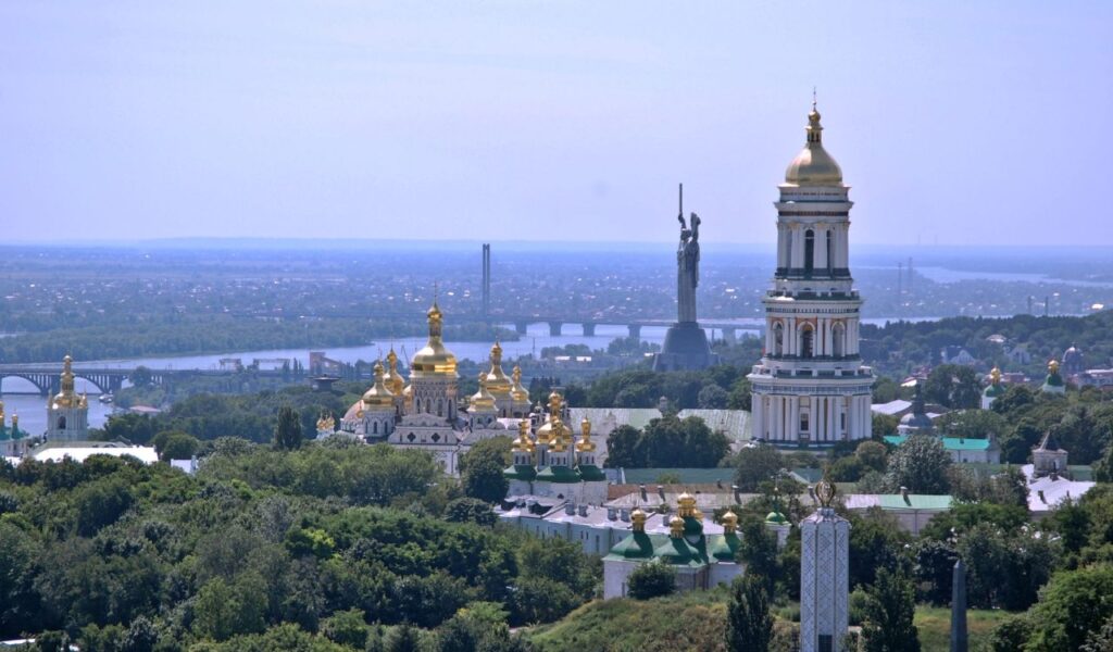 Skyline of Kiev, Ukraine, featuring golden-domed churches, the Dnieper River, and the towering Motherland Monument.