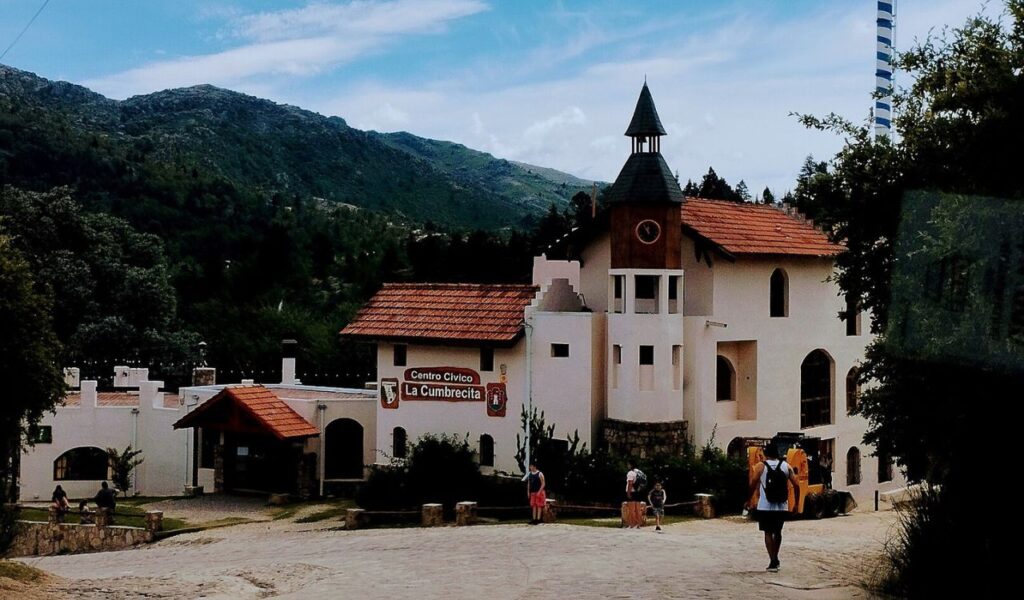 Alpine-style civic building in La Cumbrecita, Argentina, surrounded by green mountains.
