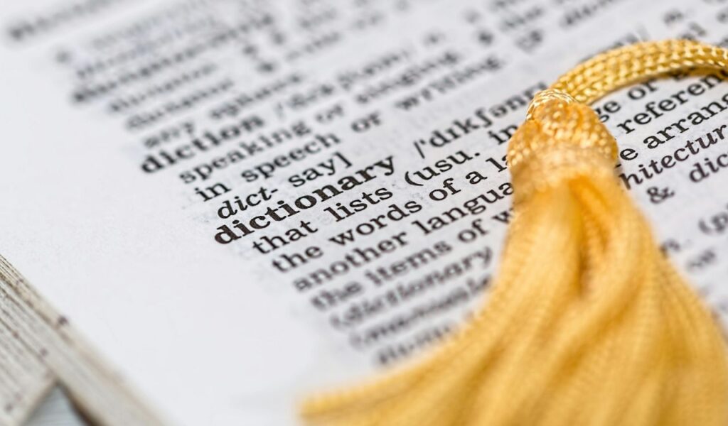 Close-up of a dictionary page highlighting the word “dictionary,” with a yellow tassel bookmark visible on the right.