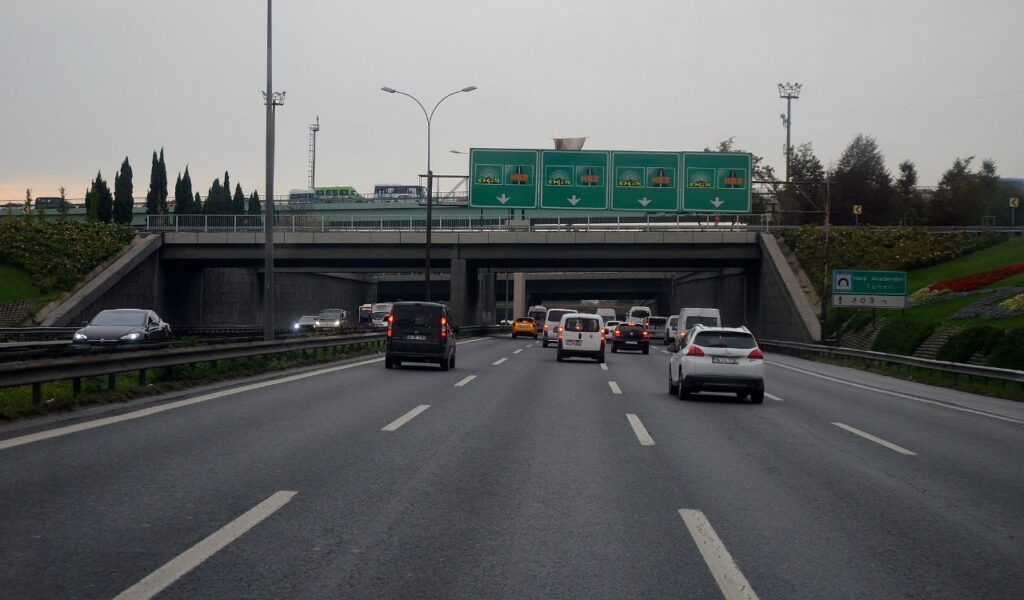 Cars driving on a multi-lane highway with noticeable gaps between vehicles, illustrating safe following distance.