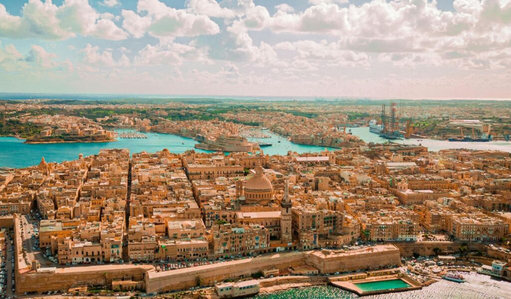 Aerial view of Valletta, Malta with historic buildings and turquoise harbor waters.