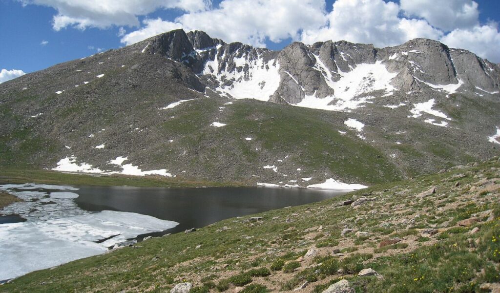 Snow-dotted peaks and alpine lake along Mount Evans Scenic Byway in Colorado.
