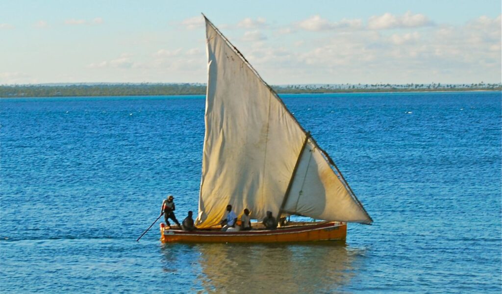 Traditional dhow boat with sail gliding across the blue waters off the coast of Mozambique.