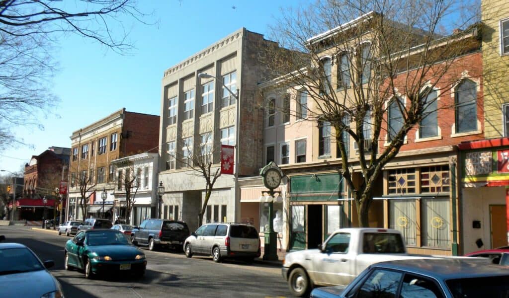 Historic downtown street in New Jersey with parked cars, old brick buildings, and a classic street clock on the sidewalk.