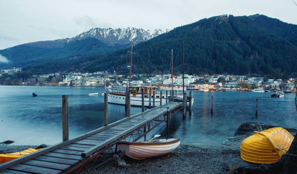 Queenstown harbor with boats and mountain backdrop in New Zealand at twilight.