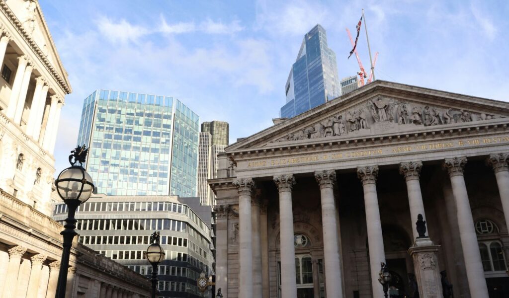 Classical-style bank building with columns in front of modern skyscrapers in a financial district, symbolizing global banking.