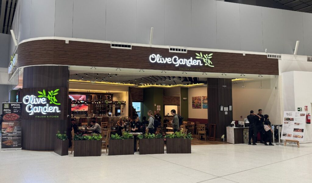 Exterior view of Olive Garden restaurant with diners seated inside.