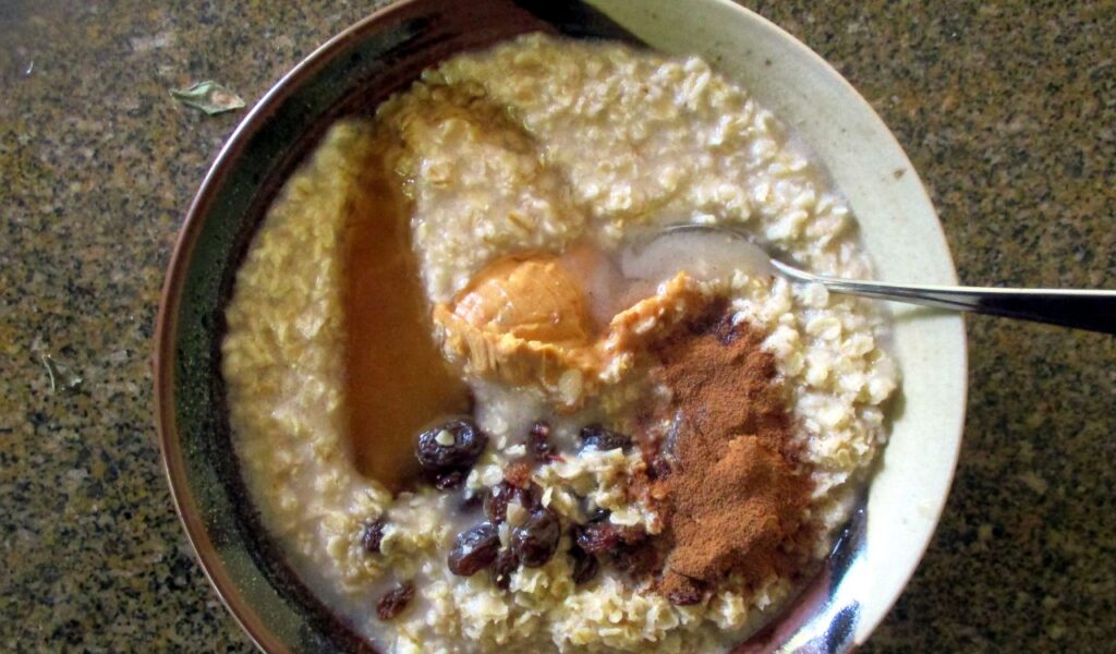 Bowl of overnight oats topped with peanut butter, raisins, and cinnamon.