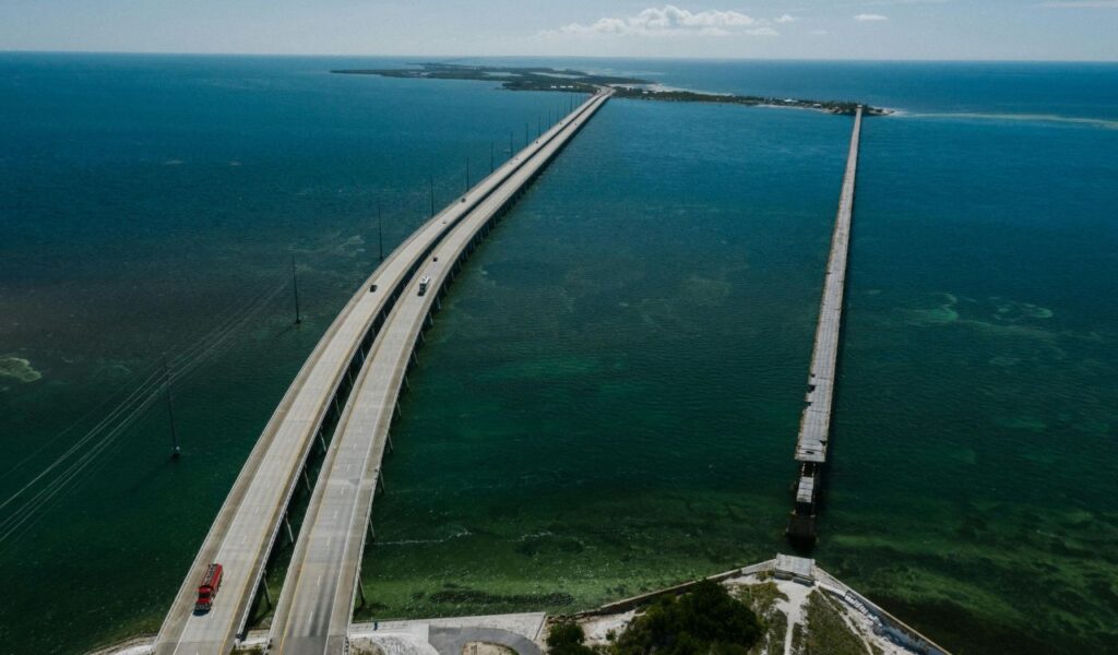 Aerial view of the Overseas Highway in the Florida Keys, featuring a long bridge stretching across turquoise waters with vehicles traveling along it.