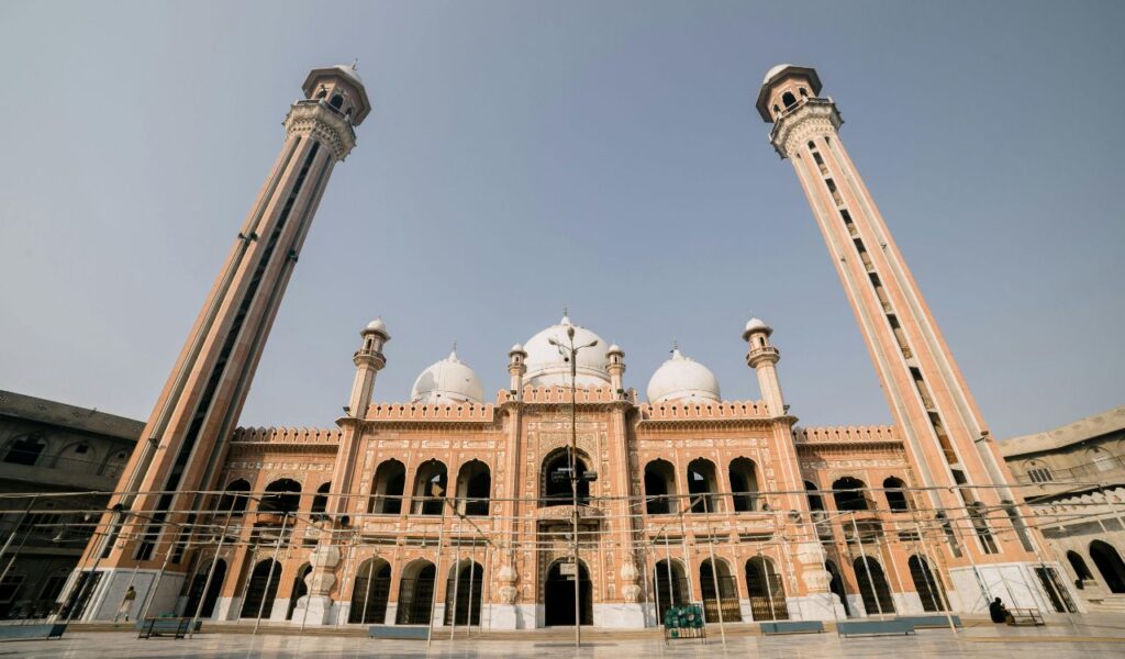 Front view of a grand mosque with twin minarets in Pakistan under clear sky.
