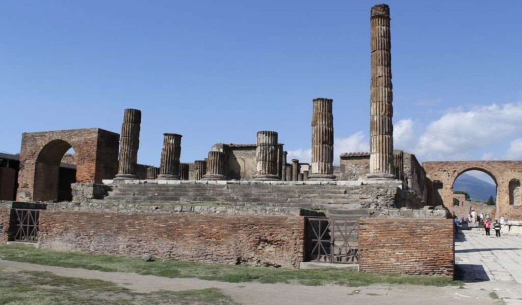 Ruins of the Temple of Jupiter in Rome, with standing columns and brick arches under a clear blue sky