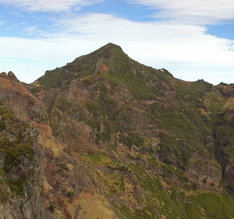 Mountain landscape view of Pico Ruivo, the highest peak in Madeira, Portugal, with rugged green and rocky terrain.