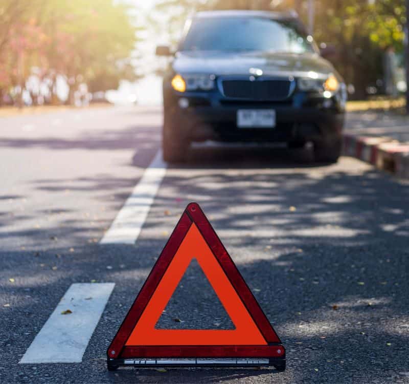 Car pausing at a Main Street crosswalk in a small town or at a scenic overlook with others parked neatly.