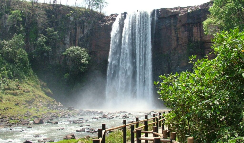 Waterfall cascading from cliffs near a wooden path, Rio Sucuri, Brazil.