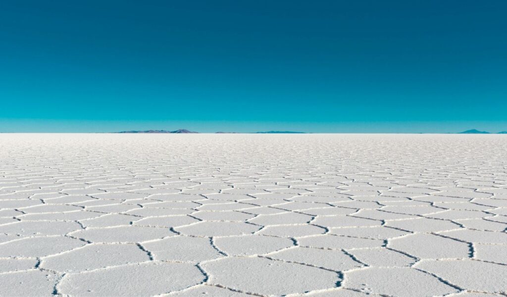 Salar de Uyuni in Bolivia with vast white salt flats stretching to the horizon under a clear blue sky.