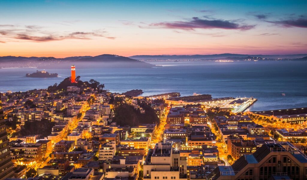 San Diego cityscape at dusk with illuminated streets, waterfront views, and vibrant skyline overlooking the Pacific Ocean.