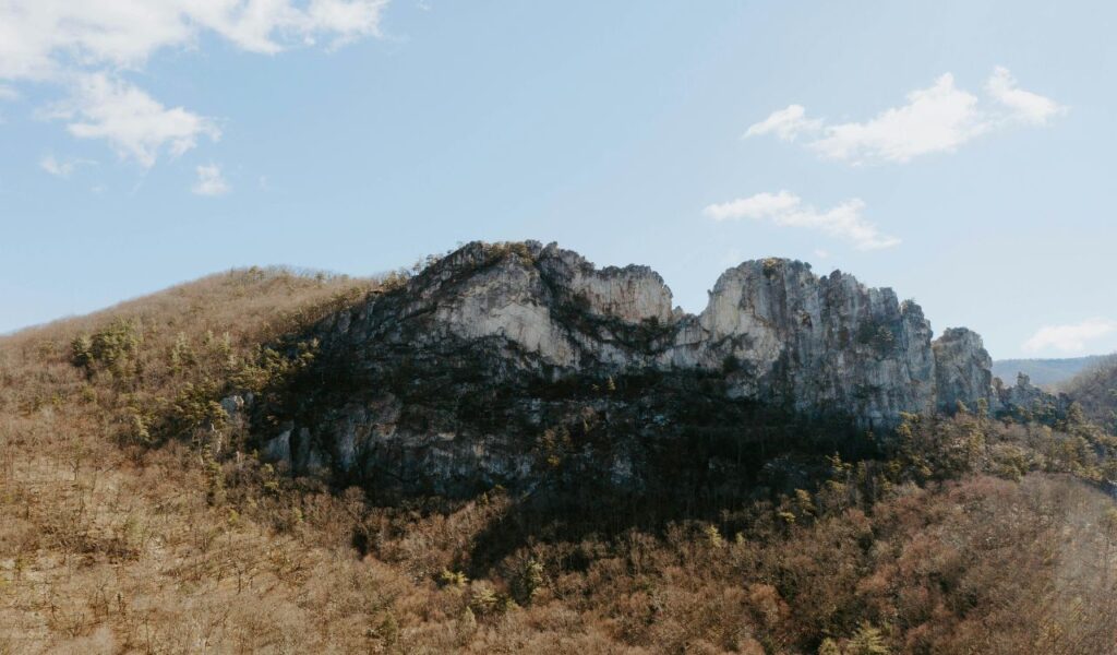 Seneca Rocks rise sharply above the forested landscape of Monongahela National Forest, with leafless trees and a clear blue sky.