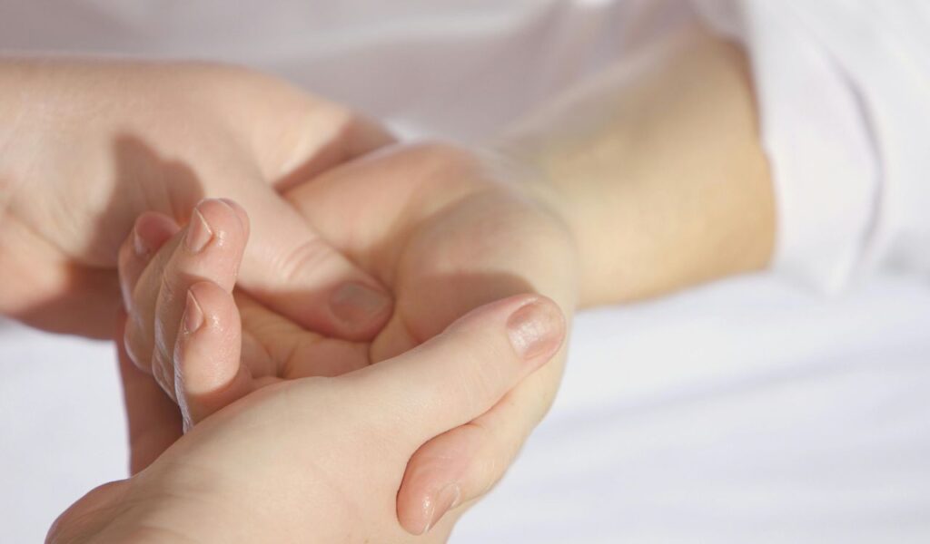 A close-up of a hand being held gently, with the palm facing upward, conveying care and attention in a soft-lit setting.