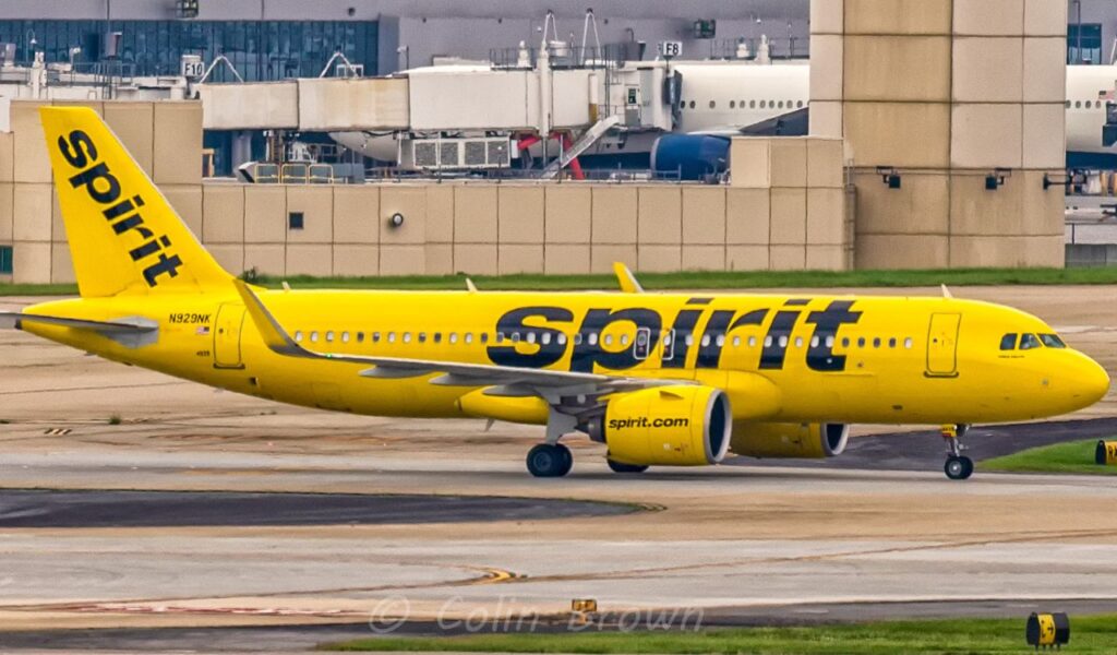 Spirit Airlines jet taxis in its signature bright yellow paint, boldly displaying the black "Spirit" logo.