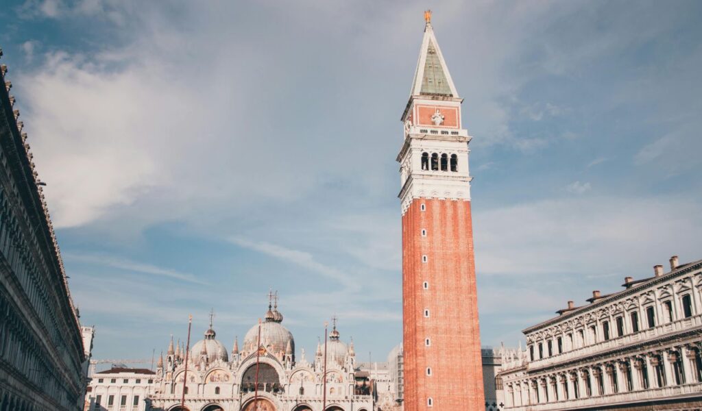 Historic St. Mark’s Lighthouse stands tall against a blue sky, surrounded by classic architecture and open square space.