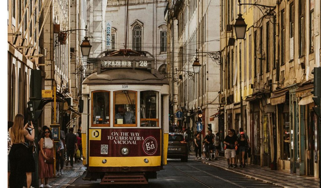 Vintage tram moving through a narrow European street with tourists walking, symbolizing free local walking tours
