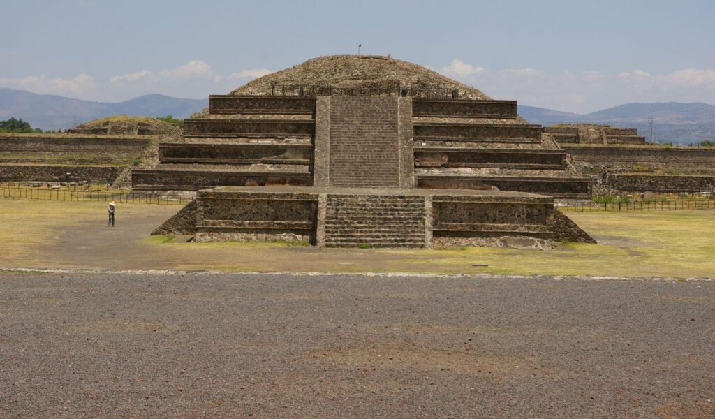 Front view of the stepped Temple of the Feathered Serpent in Teotihuacan, Mexico, with stone staircases and terraces.