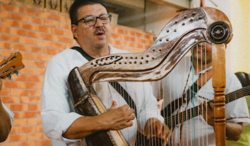 A man passionately playing the harp, accompanied by another musician with a guitar, creating a lively atmosphere with traditional music.